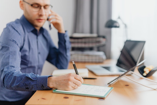 property managers at their desk on the phone while taking notes in a notebook